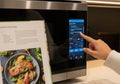 Of a person using a smart oven with a cookbook on the counter nearby Royalty Free Stock Photo