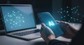 Person using smartphone with AI text and laptop in background Royalty Free Stock Photo
