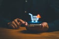 Person using smartphone with a glowing digital shopping cart and warning icon, representing online shopping error Royalty Free Stock Photo