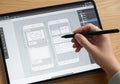A person is using a stylus on a tablet to design a mobile application interface. The screen Royalty Free Stock Photo