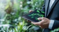 Person using tablet in lush green environment to analyze data trends and growth patterns Royalty Free Stock Photo