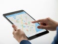 A person is using a tablet to interact with a digital map application, with various locations marked by different colored icons. Royalty Free Stock Photo
