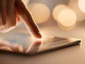 Person using touch gesture on a sleek digital tablet screen with soft glowing bokeh lights in the background creating a modern and Royalty Free Stock Photo