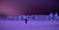 Person walking across a snow covered tundra at night