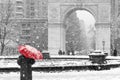 Person with red umbrella in black and white winter scene in New York City