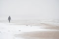 Person walking alone in the snowstorm at the beach. Winter minimalistc landscape Royalty Free Stock Photo