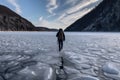 person, walking through frozen fjord, with snowshoes and backpack visible