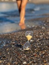 Person walking near Hourglass on the beach at the seashore Royalty Free Stock Photo