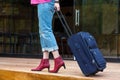 Person walking on wooden terrace pulling Travel Suitcase Royalty Free Stock Photo