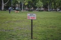 A person walks with a dog in a territory where it is forbidden to walk a dog, a Hungarian sign is on the lawn