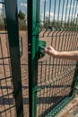 person wants get in on playground through the little gate of welded wire mesh Royalty Free Stock Photo