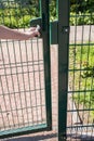 Person wants get in on playground through the little gate of welded wire Royalty Free Stock Photo