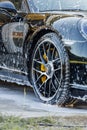 Person washing a black sports car covered in covered in soap setting