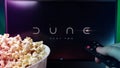 Person watching Dune Part Two movie with popcorn and remote control. Stock editorial photo.