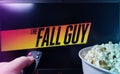 Person watching The Fall Guy on TV with popcorn and remote control. Stock editorial photo.