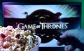 Person watching Game of Thrones series with popcorn and remote control. Stock editorial photo.