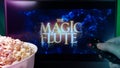 Person watching Magic Flute on TV with popcorn and remote control. Stock editorial photo.