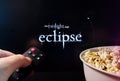 Person watching The Twilight Saga: Eclipse with popcorn and remote control. Stock editorial photo.