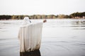 Person wearing a biblical robe standing in the water with a hand up shot from behind