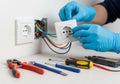 A person wearing blue gloves is installing an electrical socket. Several tools, including pliers, Royalty Free Stock Photo