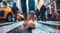 A person, wearing brown boots, walks down a city street sidewalk