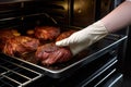 person wearing gloves placing beef roast in oven