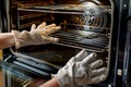 person wearing gloves scrubbing an electric oven interior