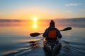 person wearing a life jacket paddling on calm waters at sunrise Royalty Free Stock Photo