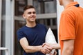 A person wearing an orange T-shirt is delivering a parcel to a satisfied client. Friendly worker, high quality delivery Royalty Free Stock Photo