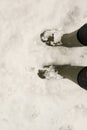A person wearing a pair of traditional green rubber wellington boots on the snow. Personal point of view