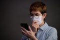 Person wearing surgical mask and using their phone looking worried and concerned about the pandemic outbreak and news from social