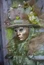 Person wearing a Venice mask and a green and gold costume at the Venice Carnival in Venice Italy