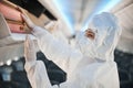 Flight attendant in safety coverall hiding luggage in overhead bin