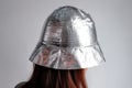 A person wears a small handmade hat made of aluminium foil on a light background to protect himself from radiation and conspiracy