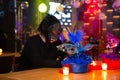 Person in a werewolf mask at a festive table with colorful masquerade masks and candles, vibrant party atmosphere