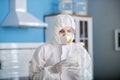 Person in white workwear and gloves holding antiseptic in hands