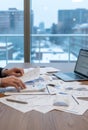 A person is working at a desk cluttered with documents, charts, and a pen Royalty Free Stock Photo