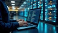 Person working on laptop in server room. Coding tasks displayed on laptop screen. Server racks with lights in background. Tech Royalty Free Stock Photo