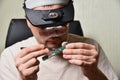A person works with an electronic board using tweezers and magnifying glasses with backlight Royalty Free Stock Photo