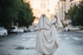 Person wrapped in blanket in the middle of empty city road early in the morning