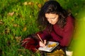 Person writes notes lying on the lawn in the autumn park. Solitude with yourself