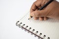 A person writing on a blank white notebook with a sharpened black pencil