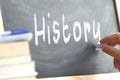 A person writing the word History on a blackboard.