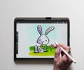 Person's hand drawing a cartoon Easter rabbit on an iPad Pro using an Apple Pencil