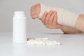 A person& x27;s hand with an elastic bandage and a jar of calcium or chondroitin tablets. Treatment of fractures, sprains