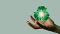 Person's hand holding a 3D rendered green recycling symbol