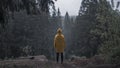 person in a yellow raincoat in a gloomy forest