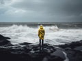 A person in a yellow raincoat standing on rocks in front of the ocean. AI generative image.