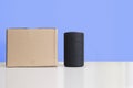 Personal assistant loudspeaker on a white wooden shelf of a smart home living room. Next, a carton box with the order Royalty Free Stock Photo