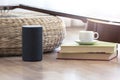 Personal assistant loudspeaker on a wooden floor of a smart home living room. Next, a guitar and some books and a cup of coffee. Royalty Free Stock Photo